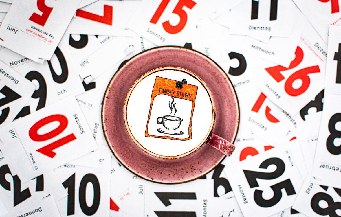 Twicky_Sticky_Kalender_in_roter_Tasse_auf_Kalenderblaetter_stehend